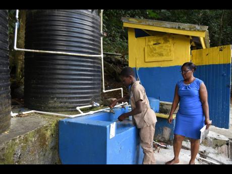 Principal Francine Taylor Arnett watches as a student washes his hands after using the toilet facilities.