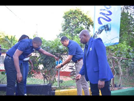 Prime Minister Andrew Holness (second right) and Robert Morgan (left), member of parliament for Clarendon North Central, take part in the commissioning of a water system in Eden, Mocho, in the parish last Friday. 
