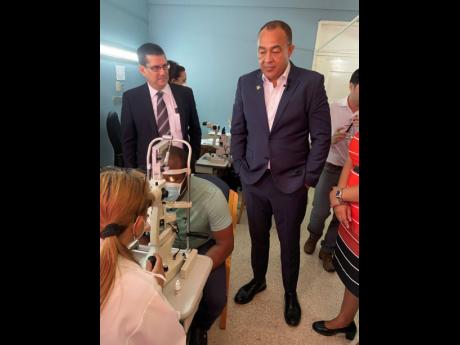 Cuban Ambassador to Jamaica, Fermin Gabriel Quinones Sanchez, and Dr Christopher Tufton, minister of health and wellness, watch as a patient is being examined at the centre on Tuesday.