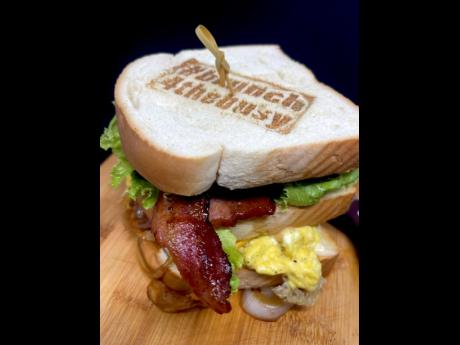 The ultimate club sandwich is filled with signature flavoured bacon, ham, turkey, eggs, caramelised onion, tomatoes, and lettuce and sauces served between two slices of bread, the top half boasting the restaurant’s stamp. 