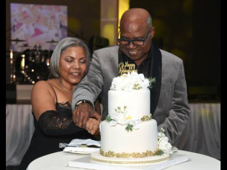 Edmund Bartlett and wife, Carmen, cut into their anniversary cake. 