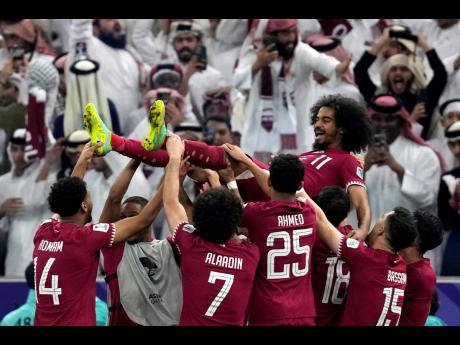 Qatar’s players throw Akram Afif in the air as they celebrate Afif’s three goals and their victory over Jordan in the Asian Cup final football match at the Lusail Stadium in Lusail, Qatar, yesterday.