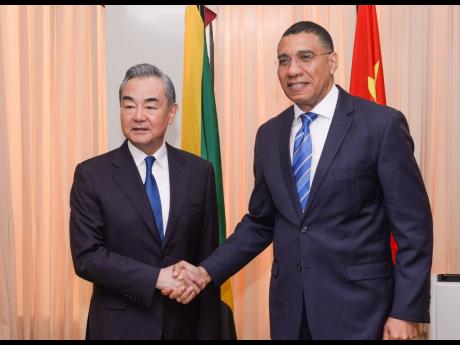 Jamaica’s Prime Minister Andrew Holness (right) shakes hands with Minister of Foreign Affairs of the People’s Republic of China, Wang Yi, shortly before a meeting at the Office of the Prime Minister last month, which involved several Cabinet ministers 