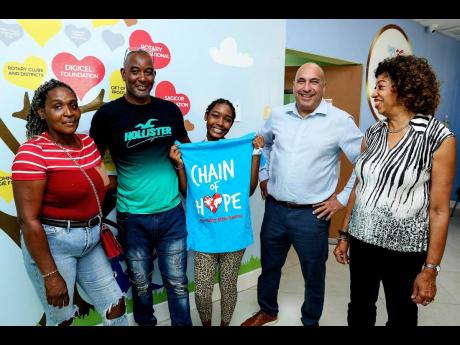 Rickayla Miller (centre) poses happily with parents Clive Miller (second left) and Nadine Austin ( left). With them are Christopher Zacca, chairman of the Sagicor Foundation, and  Diane Edwards, chairman, Chain of Hope.