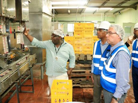 
Cal’s Manufacturing Limited’s CEO, Carlton Watson, explains the packaging process to Minister of Science, Energy, Telecommunications and Transport Daryl Vaz (right) and Factories Corporation of Jamaica’s Chairman, Lyttleton ‘Tanny’ Shirley in th
