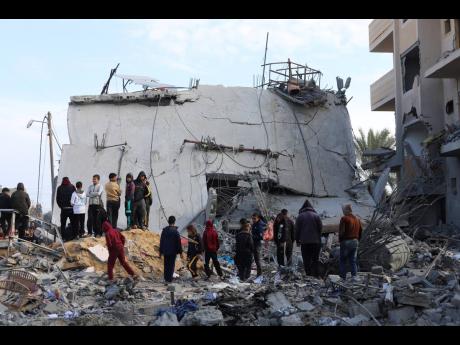 Palestinians look at the destruction after an Israeli strike on a residential building in Rafah, Gaza Strip.