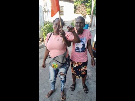 Pamella Millard and her daughter, Kimeka Rainford, showing their support by waving an orange flag and showing their fists.