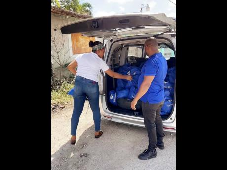 Ahead of their drive around town, Nicolette Henry (left) and Ronald Grant of Transparent BPO in Spanish Town prepared their care packages filled with ‘love’.