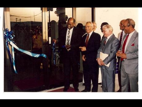 Then Minister of Public Utilities Horace Clarke cuts the ribbon of the main door at the official opening of the new Shipping Association of Jamaica (SAJ) office in Newport West. Beside him are (from second left) SAJ President Charles Johnston, past Preside