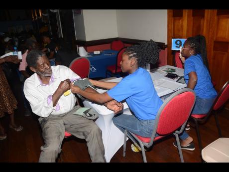 Student nurse Marissa Johns (centre) prepares participant in the Ministry of Health and Wellness’ ‘Know Your Numbers’ campaign in St James, Leslie Robinson, for a blood pressure check during the engagement’s staging in Sam Sharpe Square, Montego Ba