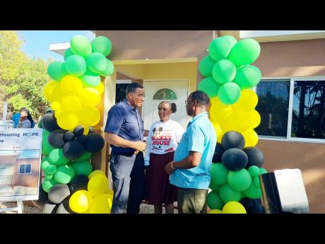 Prime Minister Andrew Holness (left) engages Adrianna Laing and her father, Adrian Laing, in a discussion on the importance of them caring for the two-bedroom dwelling gifted to them under the Government’s new social-housing programme.