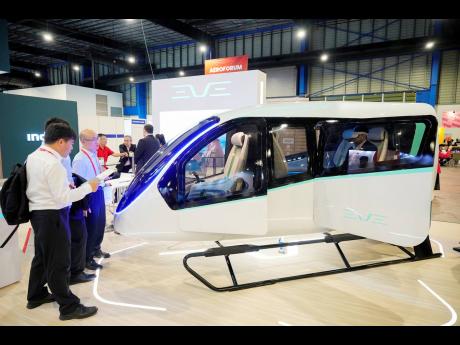 
Visitors look at Brazilian firm Eve Air Mobility, a spin-off by the third-largest aircraft manufacturer Embraer, in Singapore yesterday. As the aviation sector seeks ways to make air travel less polluting and more sustainable, aerospace company Embraer an
