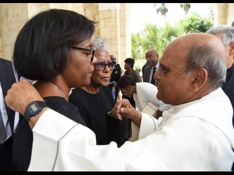 Monsignor Gregory Ramkissoon (right) gives words of support to Janet Morrison (centre), widow of Justice Cecil Dennis Harrington Morrison, and daughter Gisele Gibson (left) on Thursday following the service of thanksgiving for the late jurist at The Univer