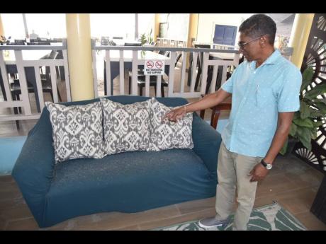 Richard Wallace, managing director of Boardwalk Village in Negril, points to soot and ash on the furniture at the resort caused by the fire in the Negril Great Morass.