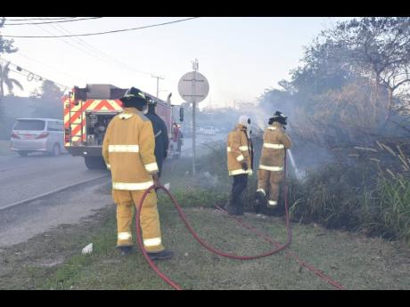 Firefighters responding to the Negril Great Morass fire along the Norman Washington Boulevard in Negril on Thursday.