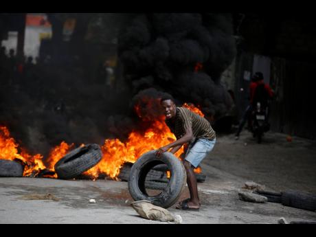 A protester adds tyres to a burning barricade during a demonstration demanding the resignation of Prime Minister Ariel Henry, in Port-au-Prince, Haiti.