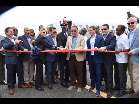 Minister of Transport, Daryl Vaz (centre), being assisted by the American Eagle crew, executives of the Airports Authority of Jamaica, American Airlines and Sandals Resorts International to cut the ribbon officially welcoming the AA inaugural flight to the