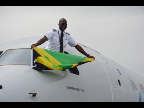 Jamaican-born captain, Marc Coley, shows off his Jamaican flag after landing the Embraer 175 American Eagle aircraft with 71 passengers on board at the Ian Fleming International Airport in Boscobel, St Mary, on Saturday afternoon.
