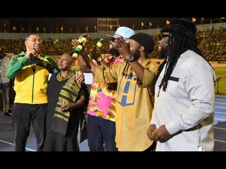 From left, Prime Minister Andrew Holness with Olivia Grange Minister of Sports, Youth and Culture after presenting  Morgan Heritage's Gramps, Peetah and Mr Mojo with the Icon Award  at the  Independence Grand Gala at National Stadium in Kingston on Sunday,