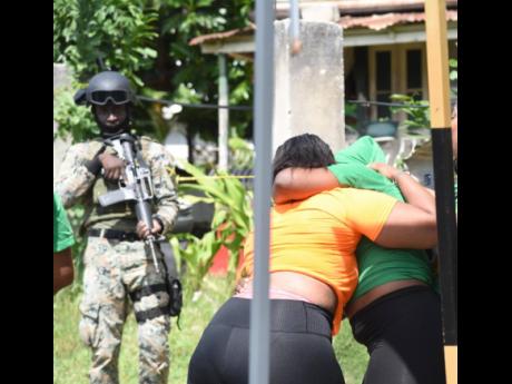 United in grief: A PNP and a JLP supporter console each other in Flankers, St James, after a man was reportedly shot dead under controversial circumstances by members of the security forces on Monday.
