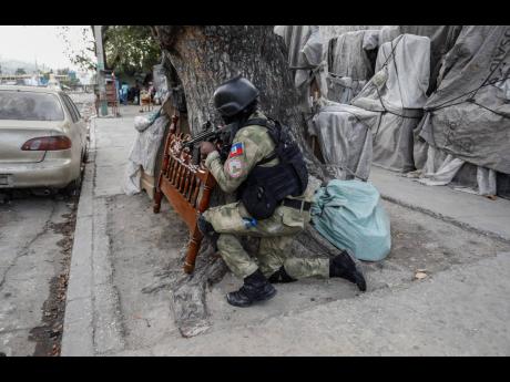 Police take cover during an anti-gang operation at the Portail neighborhood of Port-au-Prince, Haiti on Thursday