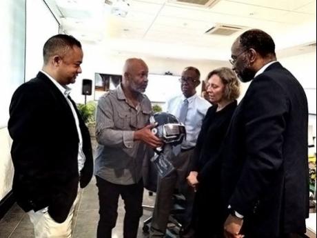 Conrad Wiggan (second left), chairman of Island Bikers Association, explains how to check if a helmet is of the best quality to Parris Lyew–Ayee (left), vice–president of the Private Sector Organisation of Jamaica; Dr Lucien Jones (centre), chairman, N
