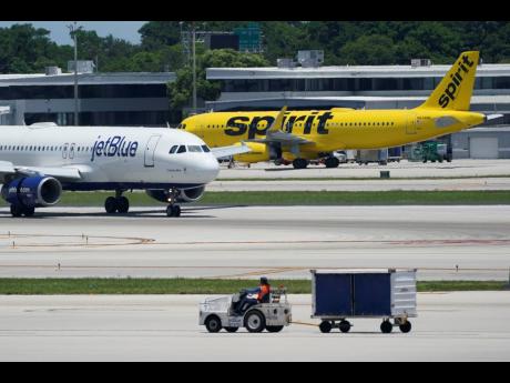 A JetBlue Airways Airbus A320 (left) passes a Spirit Airlines Airbus A320 as it taxis on the runway, July 7, 2022, at the Fort Lauderdale-Hollywood International Airport in Fort Lauderdale, Florida.
