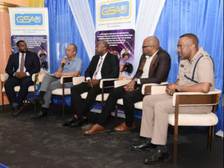 Senior Superintendent of Police Vernon Ellis (right) looks on as Dr Horace Chang (second left), minister of national security, addresses the audience during the Global Services Association of Jamaica President’s Breakfast Forum at the Grand-A-View Event 
