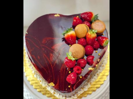 The raspberry mousse cake with raspberry chocolate mirror glaze, topped with fresh strawberries and macarons. 