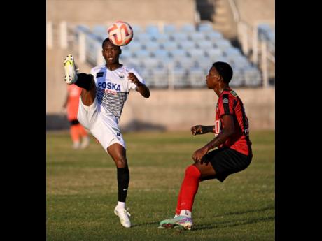 Cavalier’s Dwayne Atkinson (left) controls the ball ahead of  Arnett Garden’s Warner Brown during a rescheduled Jamaica Premier League match at Sabina Park on January 7.