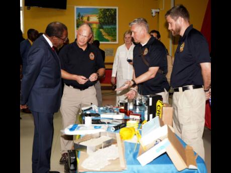 The United States’ (US) Federal Bureau of Investigation’s (FBI) evidence response team lead Sterling Mueller (second left) alongside other members of the FBI team sharing details on tools used as part of evidence collection training with US Ambassador 