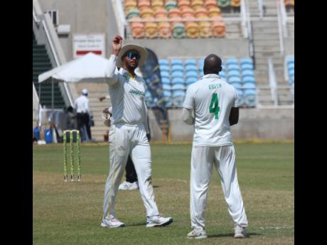 Jamaica Scorpions captain Brandon King (left) throws the ball to fast bowler Derval Green during yesterday’s third day of the West Indies Championship cricket match against the West Indies Academy at Sabina Park.  