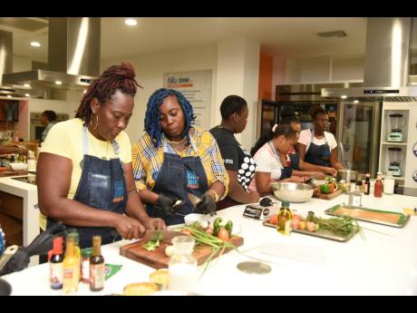 In this 2023 photo parents are seen preparing macaroni and cheese during the launch of the the Project Star School Feeding programme at the Food and Drink Kitchen.
