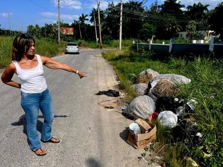 Sandra Estrada, vice-president of the Bogue Heights Citizens’ Association, points out illicitly disposed waste material along the roadway adjoining the St James-based community, an issue which has reportedly been ongoing for several years.
