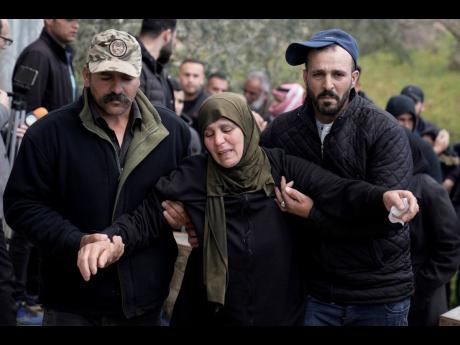 Mourners assist a relative of Fakher Bani Jaber, during his funeral in the village of Aqraba, near the West Bank city of Nablus yesterday. The 40 year-old man was shot and killed on Tuesday by an Israeli settler, according to Palestinian official news agen