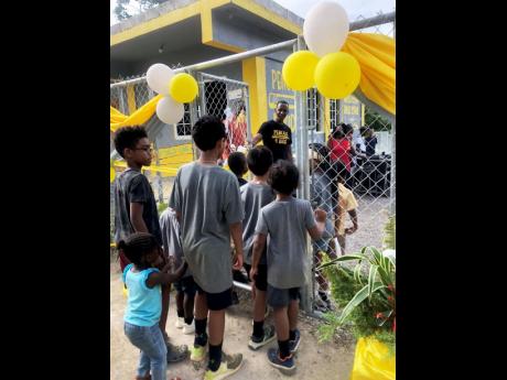 Randy Griffiths, founder of the United States-based charitable organisation Pencils 4 Kids opens the gate as he welcomes a group of boys to the playing area at Quickstep Primary and Basic School in St Elizabeth.