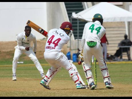 Jamaica Scorpions spinner Peat Salmon (left) dismisses Leeward Islands Hurricanes batsman Jahmar Hamilton, as wicket-keeper Romaine Morris looks on during the second day of their West Indies Championship match at Sabina Park.