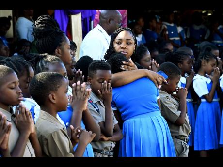 A mother consoles her daughter as teachers and students mourn the death of Principal Yvette Samuels during devotion at the Alpha Primary School on South Camp Road in Kingston yesterday.