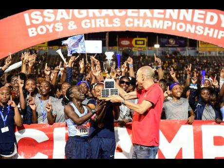 Edwin Allen High's co-captains Tonyan Beckford (left) and Monique Stewart receive the girls' champs trophy from Chief Executive Officer of GraceKennedy, Don Wehby, at the ISSA/GraceKennedy Boys and Girls' Athletics Championships at the National Stadium ton