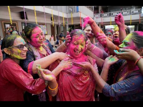 Teachers apply coloured powder on another as they celebrate Holi, the Hindu festival of colours, at a school in Ahmedabad, India, in March 2022. 