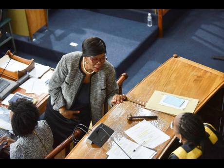 Clerk to the Houses of Parliament Valrie Curtis (standing) speaks with House Speaker Juliet Holness during yesterday's sitting of the House of Representatives. 