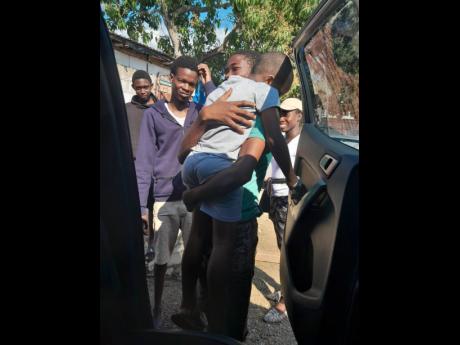 Young Domanique is hoisted from a vehicle by Kenroy McKenzie, 17, on Thursday in Palmers Cross Clarendon, happy to see the child alive. 