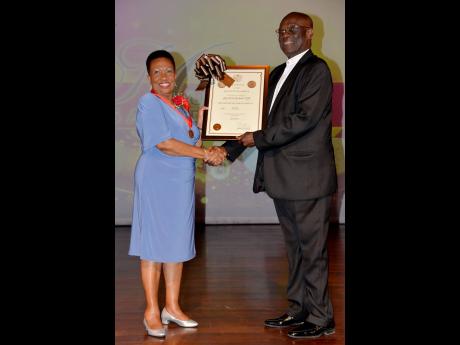 Merline Bardowell, (left), receives the bronze Musgrave Medal and certificate for the Science category from Bishop Herro Blair, chairman of council, Institute of Jamaica 