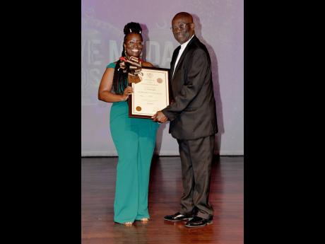 Dr. Sharma Taylor (left) receives her bronze Musgrave Medal and certificate for the Literature category from Bishop  Herro Blair.