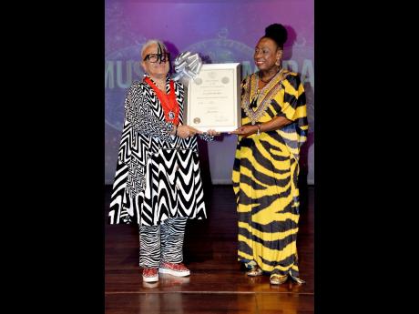 Dr. L’Antoinette Stines (left) receives her silver Musgrave Medal and certificate from Culture Minister, Olivia Grange.