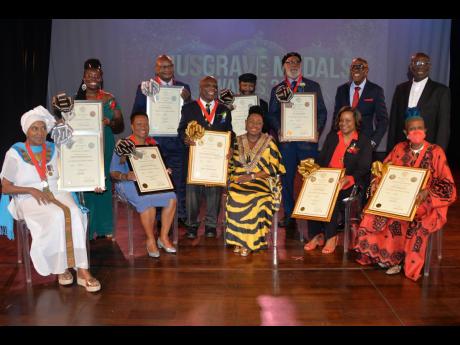Minister Grange (seated middle) is joined by Musgrave Medal Awardees from left (seated) Barbara Blake-Hannah, Merline Bardowell, Marcia Roye and Carolyn Cooper and (from left, standing) Sharma Taylor, Conrad Douglas, Vivian Crawford, George ‘Fully’ Ful