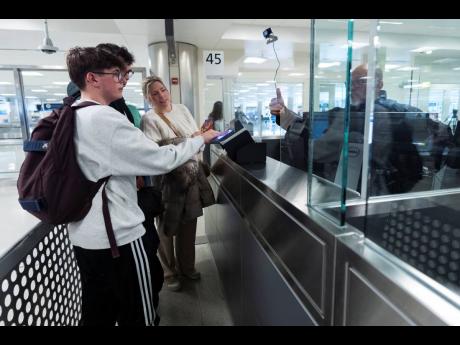 
A Custom Border Protection officer (right) puts his thumb up as Tuur de Staercke (left) gets screened in the port of entry as his family watches at Washington Dulles International Airport in Chantilly, Virginia, on Monday, April 1, 2024. The Belgian famil