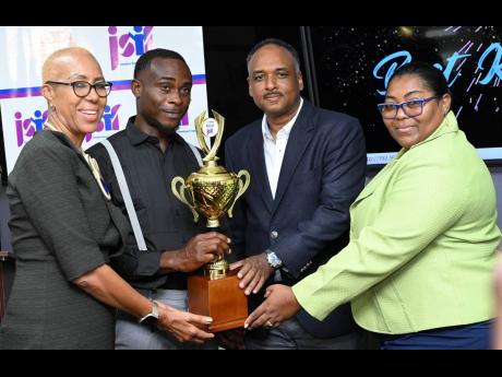 Education and Youth Minister Fayval Williams (left) and Jamaica Social Investment Fund Managing Director Omar Sweeney (second right) present the Best Kept School trophy to Shernet Clarke Tomlinson (right), principal of the Edward Seaga Primary School, and 