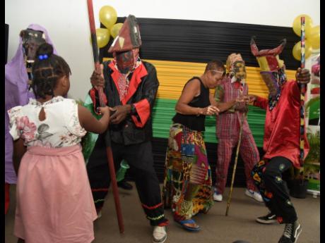 Members of the East Kingston Junkanoo Band dance with members of the audience during the media launch of the International Junkanoo Festival which was held at the African Caribbean Institute of Jamaica last Thursday.