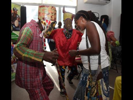 Members of the East Kingston Junkanoo Band dance with members of the audience during the media launch of the International Junkanoo Festival, which was held at the African Caribbean Institute of Jamaica last Thursday.